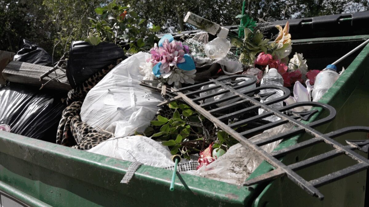 A dumpster full of trash and decorations that once adorned the graves at Our Lady of Victory Cemetery #2 in Beeville