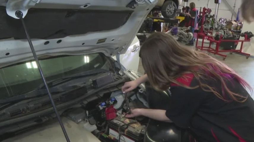 Student Ally Langley points out a bad fuse under the hood of a vehicle at Cherry Creek Innovation Campus.