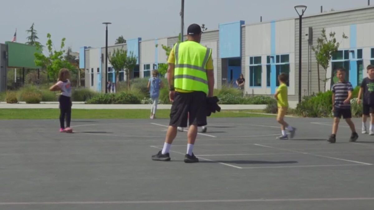 Wearing bright vests and greeting students with big smiles