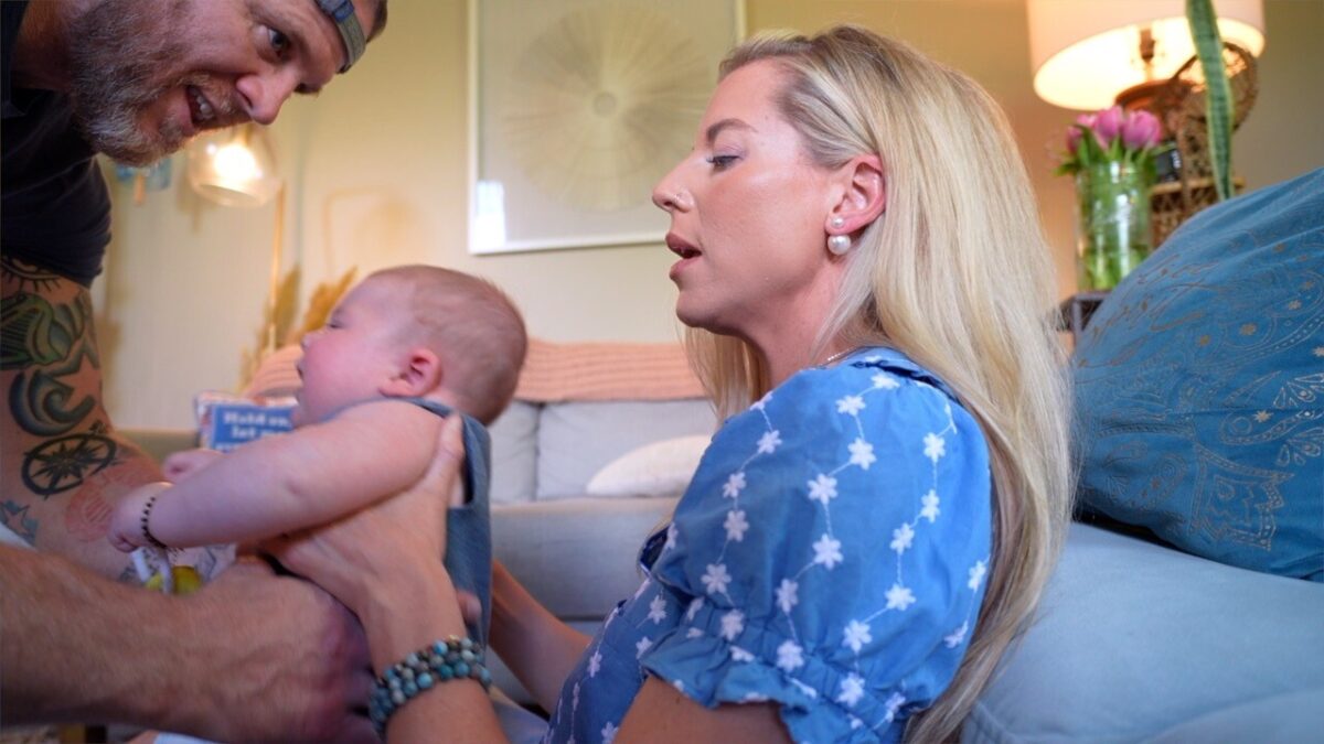 Paige Ballengee hands her 5-month-old son Jackie off to her husband before an interview.