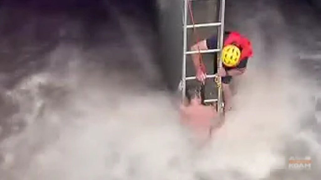 The man was clinging to a pillar as fast-moving storm water rushed around him.