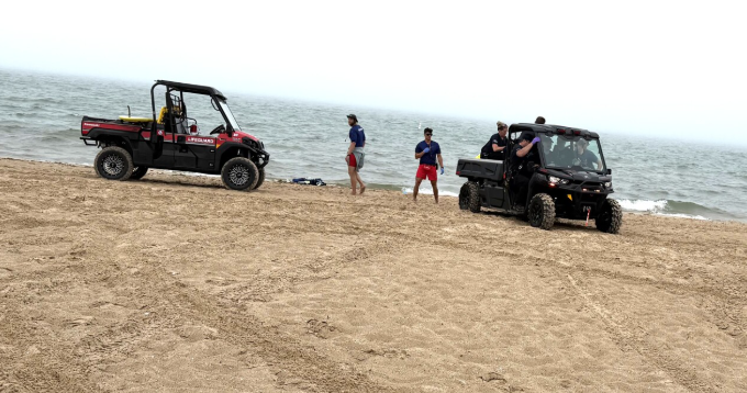 South Haven city lifeguards standby on South Beach after providing emergency care to a swimmer who collapsed on the beach.
