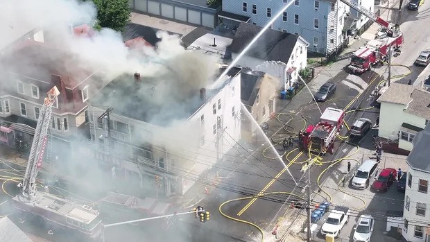A firefighter pulled a man out of a third-floor window as flames spread to three multi-family homes.