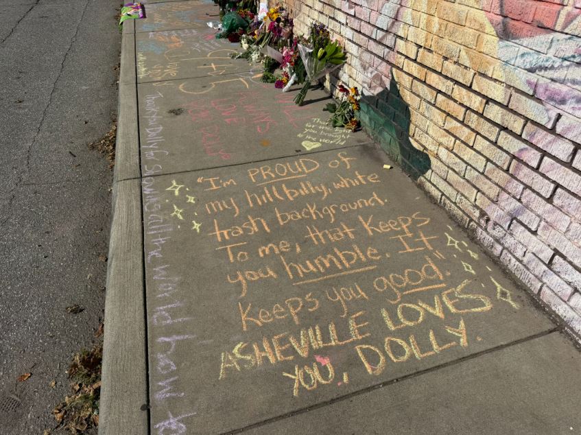 Messages written in chalk at the base of the Dolly Parton mural along Haywood Road in Asheville