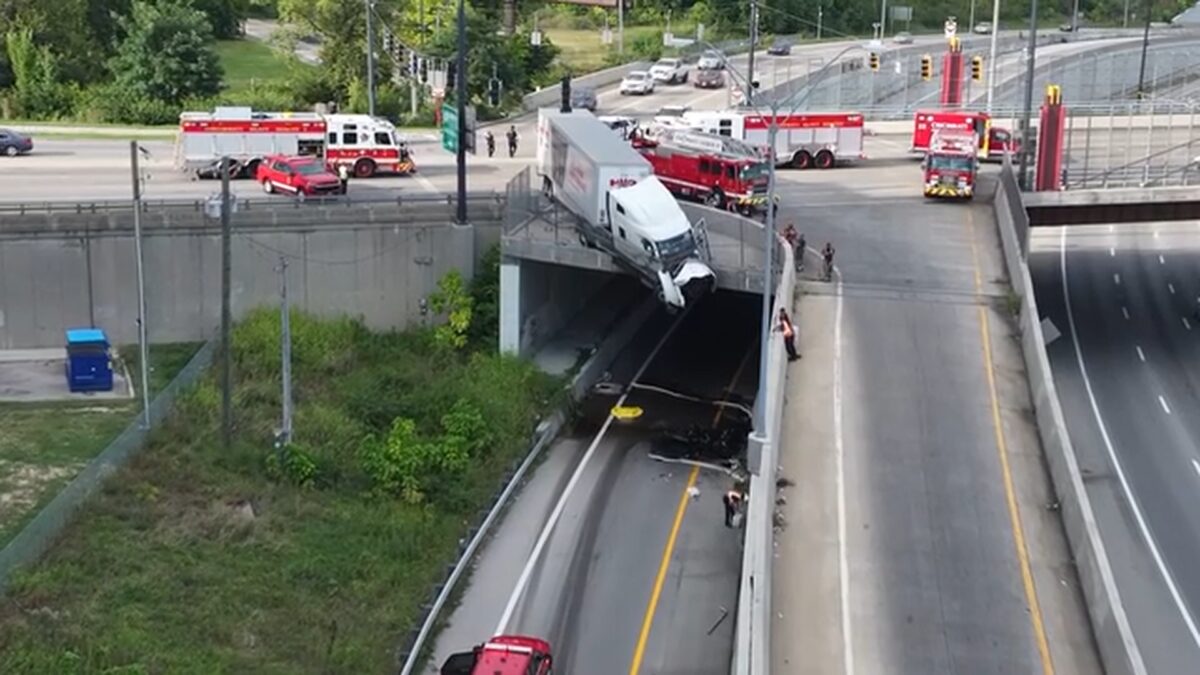 Camera captures the moments a semi truck with two people inside crashes through a guard wall and dangles over the edge of an overpass in Cincinnati.